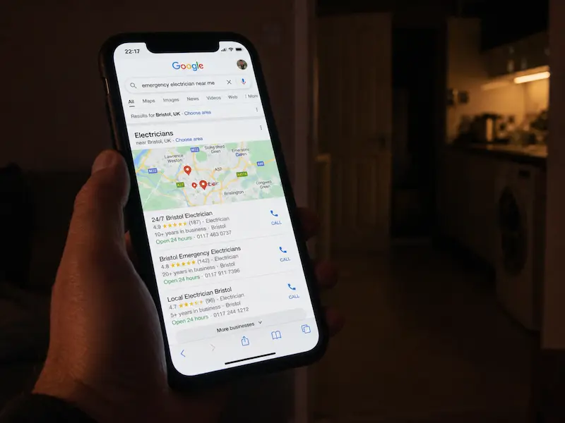 Homeowner using smartphone to search for emergency electrician at night
